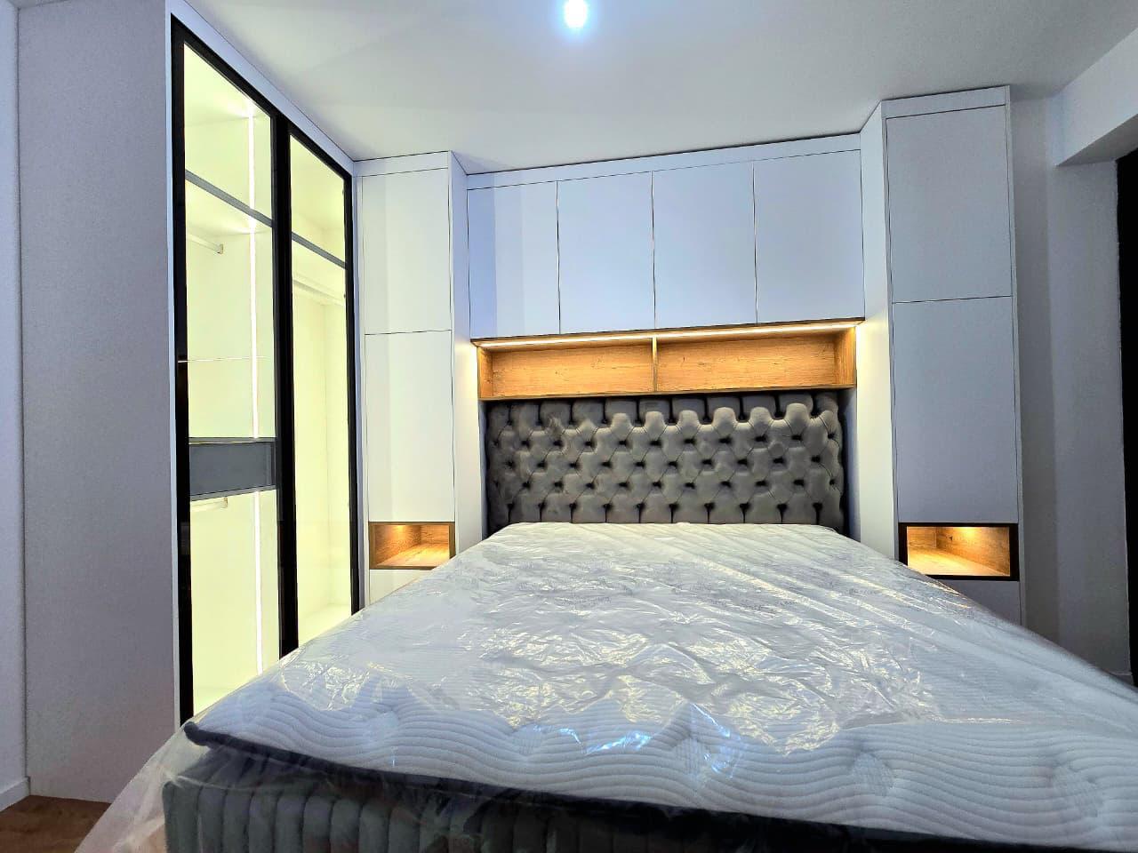 Chambre parentale avec tête de lit capitonnée grise et niche bois rétroéclairée