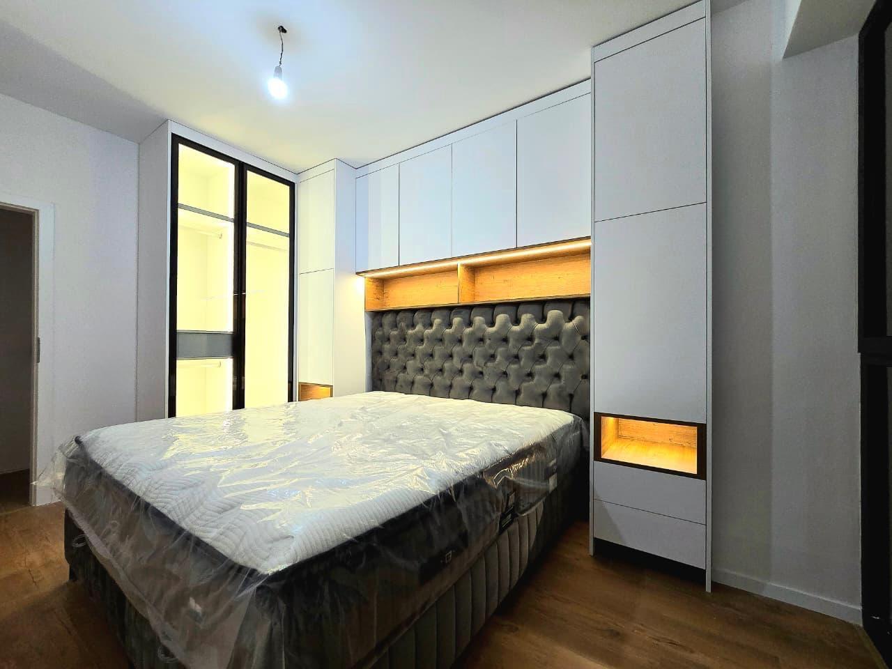 Chambre parentale avec tête de lit capitonnée grise et rangements sur-mesure